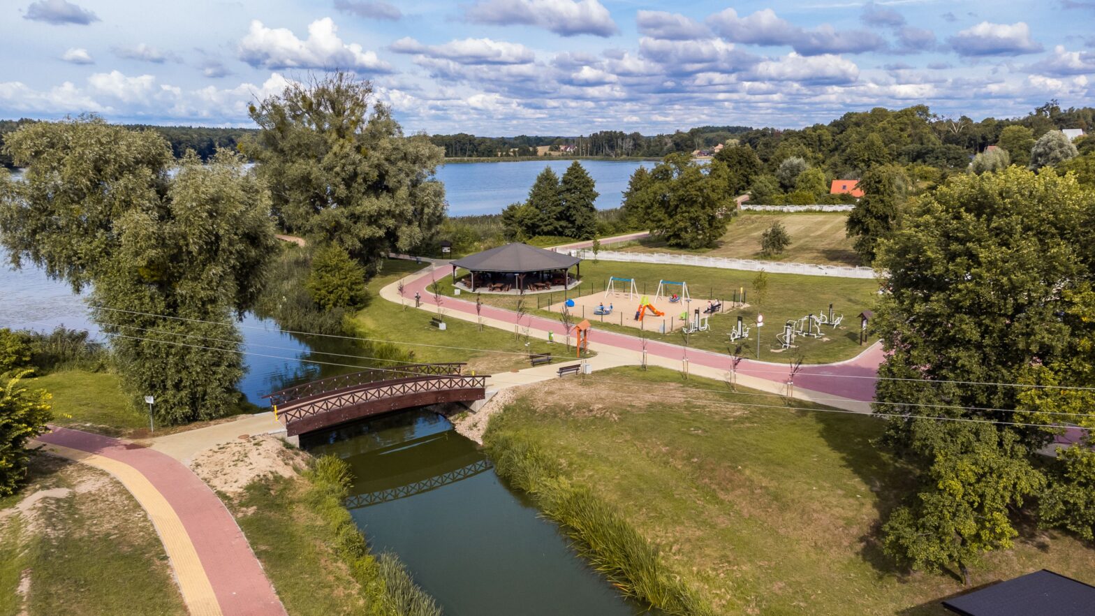 Ścieżki i kładka przy kanale i jeziorze w Gminie Dobiegniew wraz z infrastrukturą turystyczną W oddali wiata turystyczna i plac zabaw..